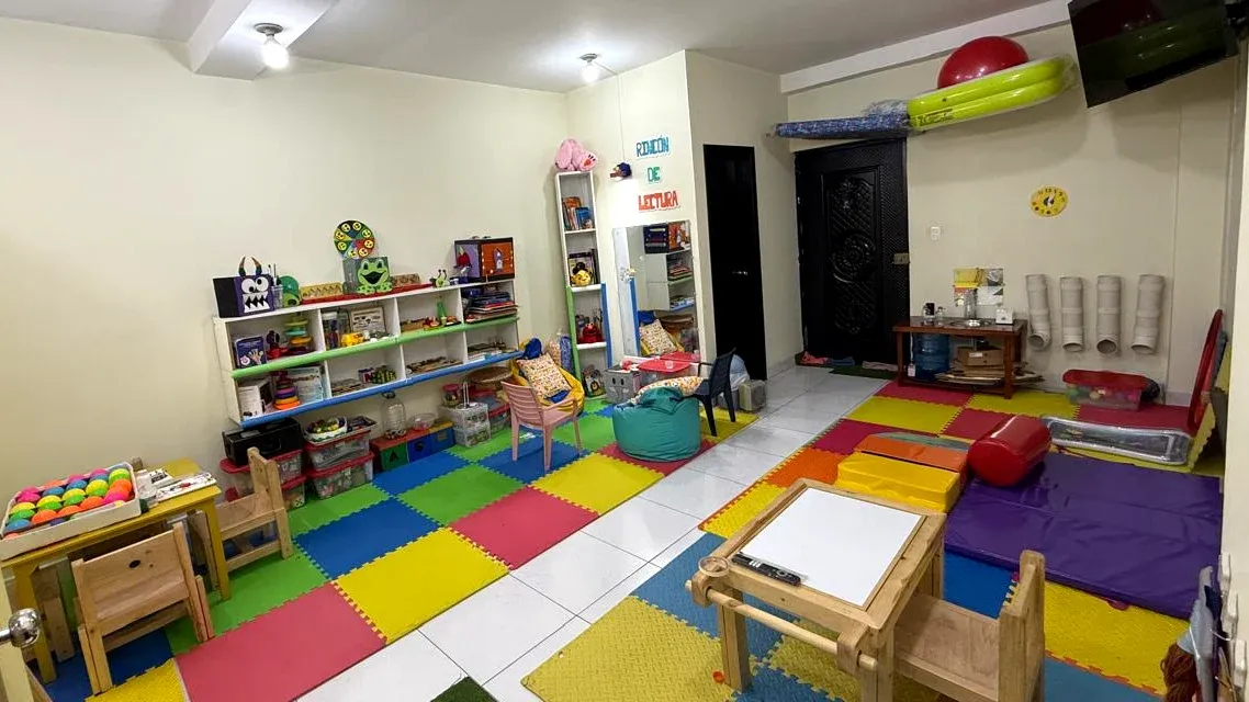 La sala de ParvuArt: piso de goma de colores, estantes con juegos, mesitas de madera y un rincón con colchonetas.